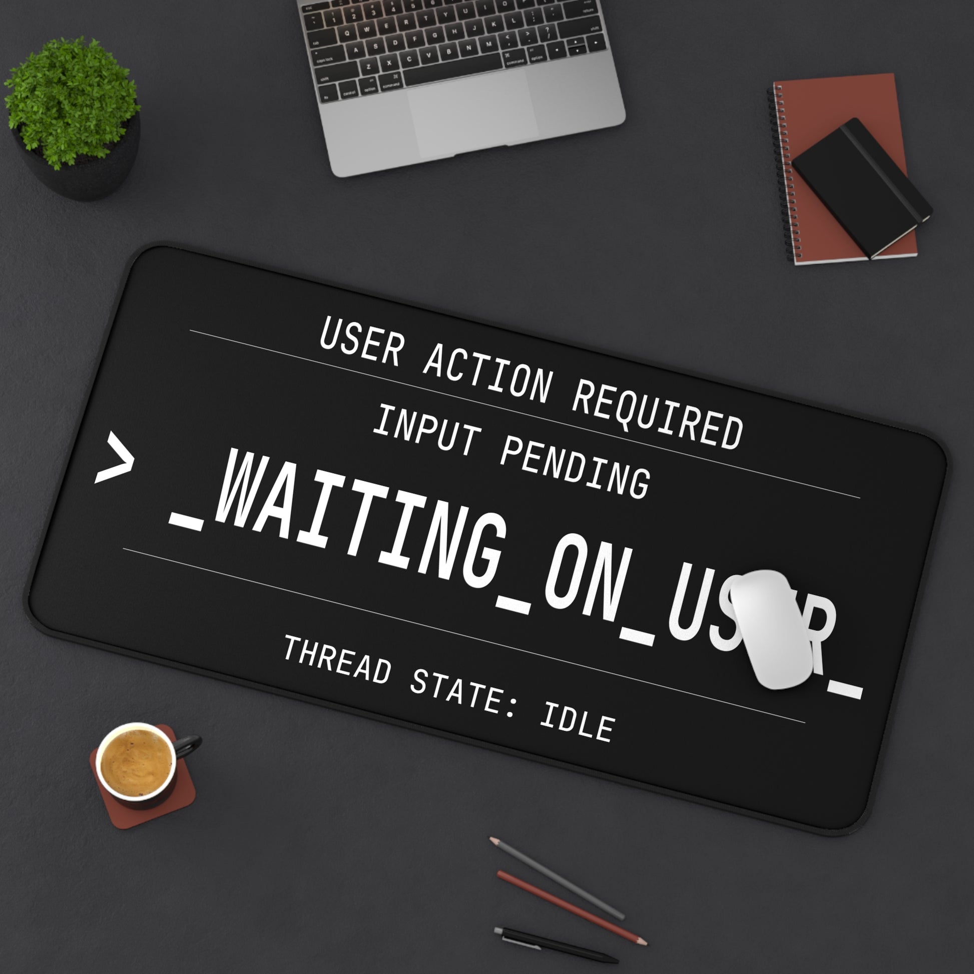 Black mouse pad with text design on a desk with laptop and coffee cup.