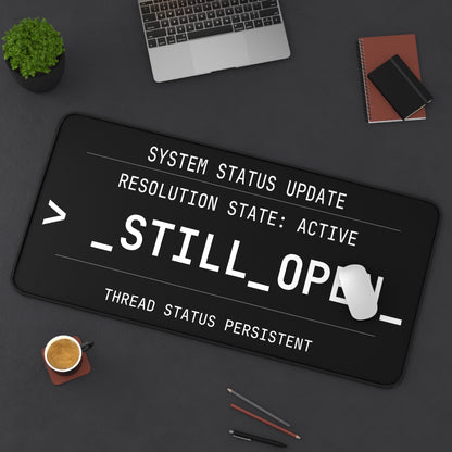Black desk mat with text design on a dark surface with office items.
