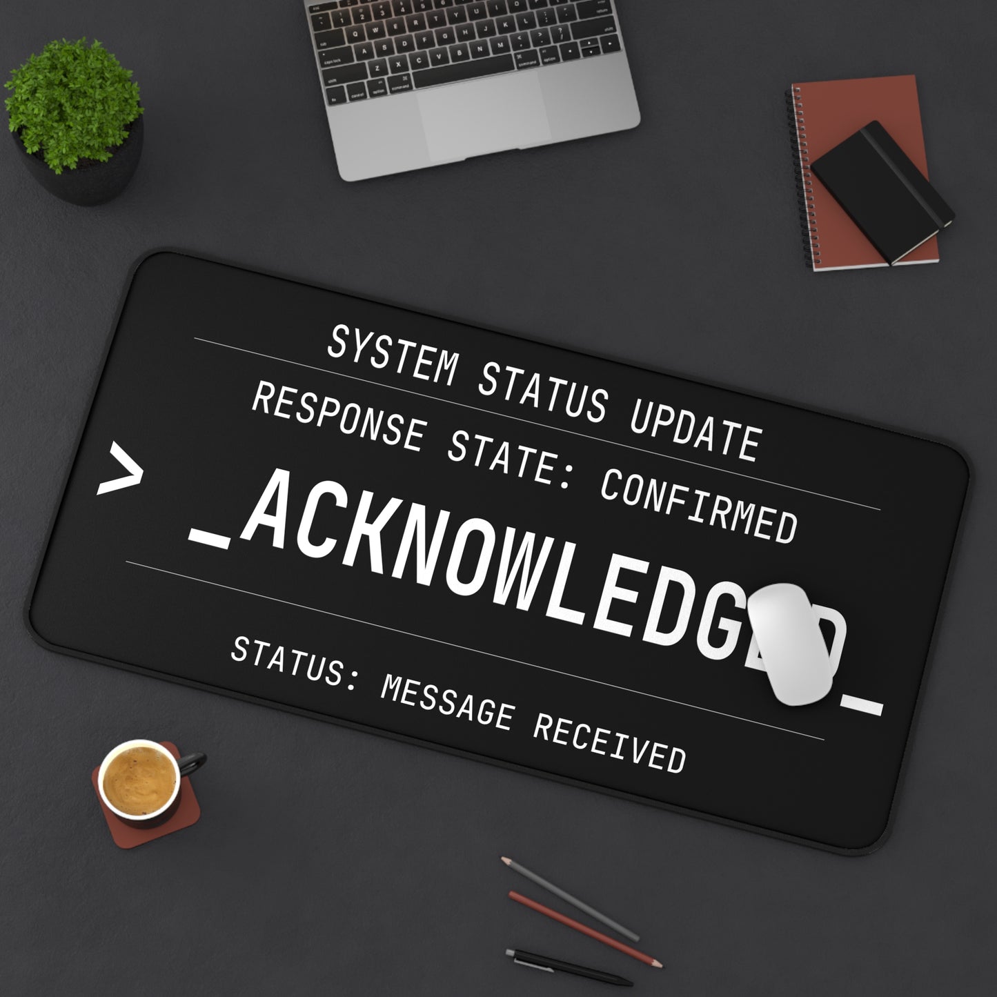 Desk setup with a large computer keyboard mat displaying text on a dark surface.