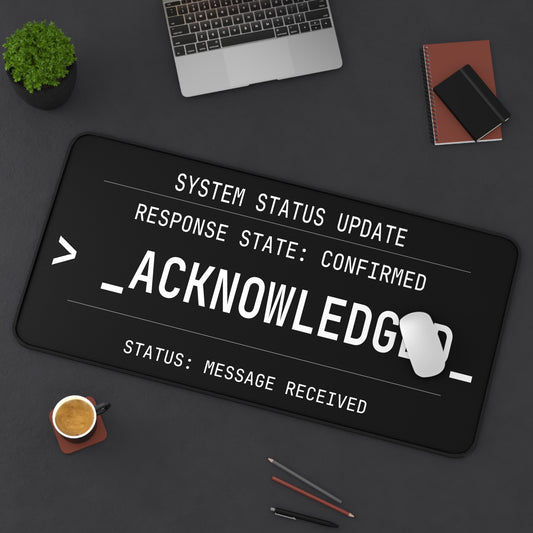 Desk setup with a large computer keyboard mat displaying text on a dark surface.